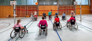 Eine Gruppe von Menschen, die im Rollstuhl sitzen und zusammen mit einem Ball spielen.