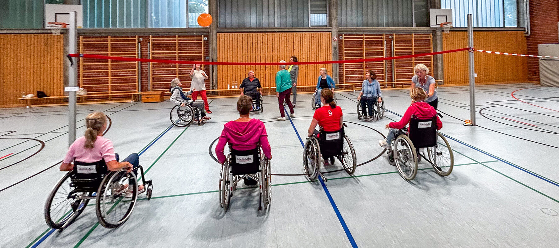 Eine Gruppe von Menschen, die im Rollstuhl sitzen und zusammen mit einem Ball spielen.